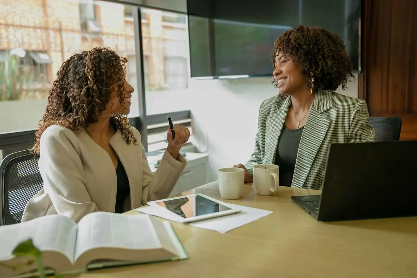 Two colleagues talking over coffee at a meeting table