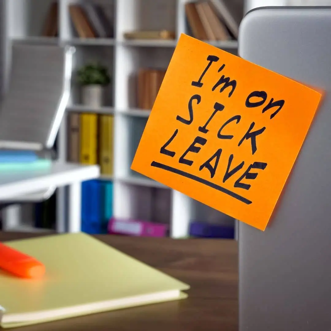 Orange sticky note reading I'm on sick leave stuck to a laptop